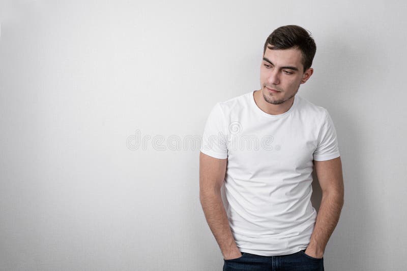 Portrait de jeune homme sûr dans le T-shirt vide blanc sur le fond gris avec l'espace de copie image libre de droits Portrait de jeune homme sûr dans le T-shirt vide blanc sur le fond gris avec l'espace de copie image libre de droits