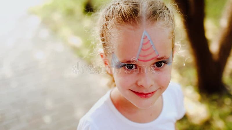 Portrait de jeune jolie fille avec de la peinture de visage comme la licorne sur son visage. banque de vidéos