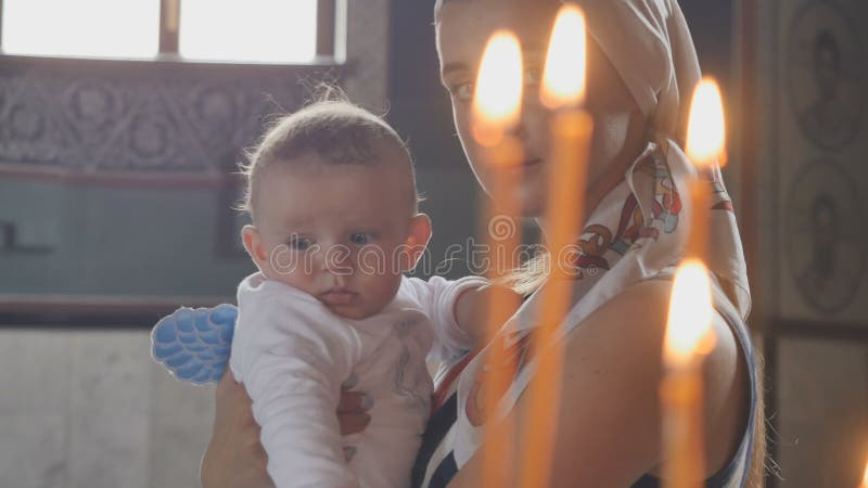 Portrait de jeune mère avec le petit fils devant des bougies dans l'église