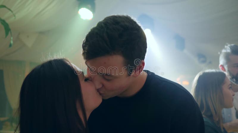Portrait de jeunes couples embrassant en atmosphère intime sur le fond des lumières lumineuses dans le club