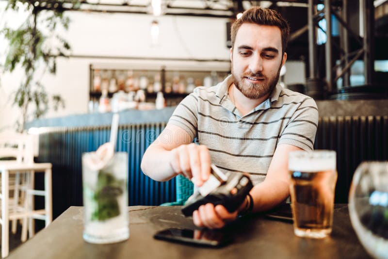 Portrait de l'homme payant au restaurant utilisant la carte de crédit et le terminal sans fil images libres de droits Portrait de l'homme payant au restaurant utilisant la carte de crédit et le terminal sans fil images libres de droits