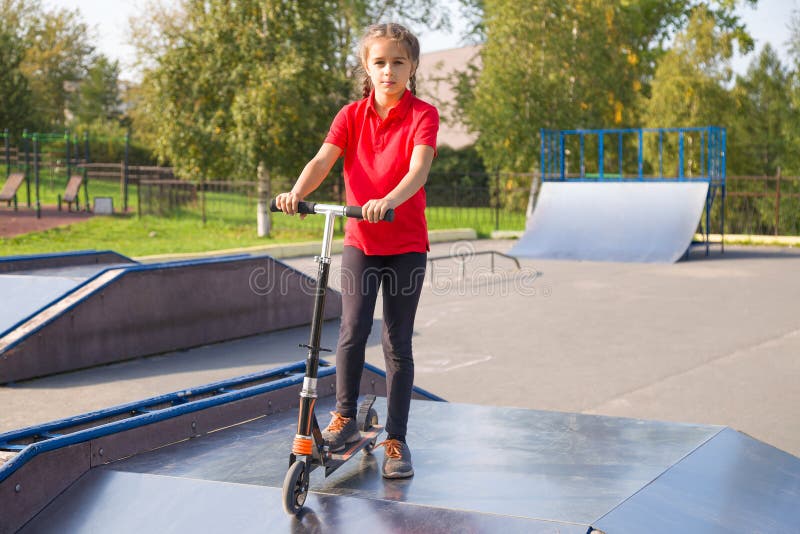 Portrait de l'équitation mignonne de petite fille sur un scooter de cick images libres de droits Portrait de l'équitation mignonne de petite fille sur un scooter de cick images libres de droits
