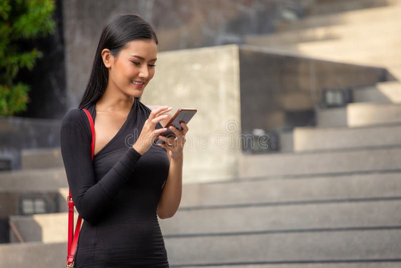 portrait de la belle jeune femme asiatique d'affaires dans la robe noire appelant avec la position de smartphone dans la ville Da photos libres de droits portrait de la belle jeune femme asiatique d'affaires dans la robe noire appelant avec la position de smartphone dans la ville Da photos libres de droits