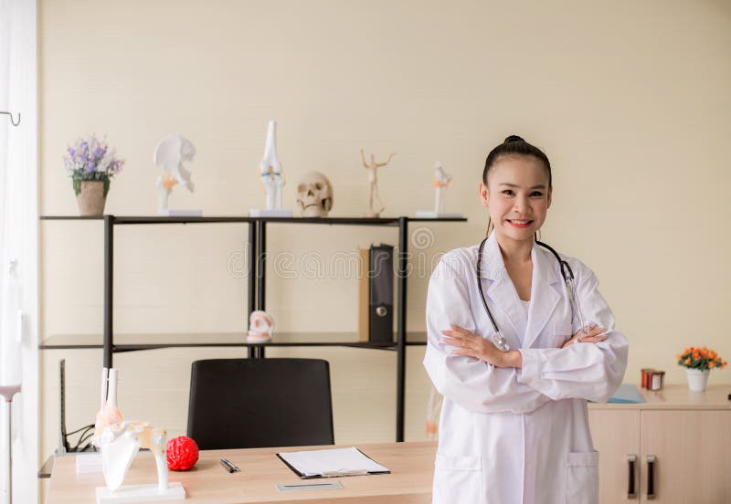 Portrait de la belle position asiatique de sourire de docteur de femme et des bras croisés regardant la caméra la pensée d'hôpita images libres de droits Portrait de la belle position asiatique de sourire de docteur de femme et des bras croisés regardant la caméra la pensée d'hôpita images libres de droits