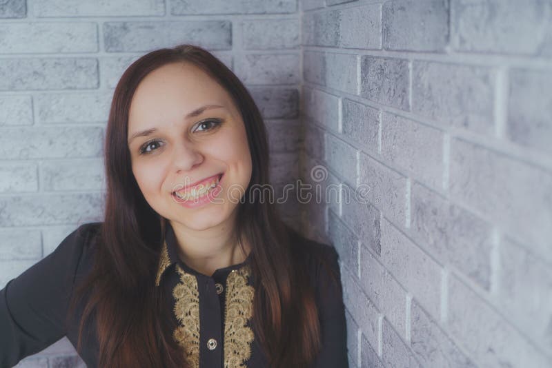 Portrait de la belle position de bonheur de jeune femme sur le fond grunge de brique de mur de texture grise de ciment photographie stock Portrait de la belle position de bonheur de jeune femme sur le fond grunge de brique de mur de texture grise de ciment photographie stock