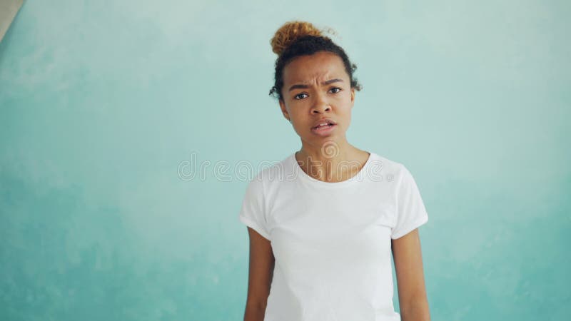 Portrait de la femme fâchée de métis parlant et faisant des gestes exprimant des émotions négatives se tenant contre bleu-clair banque de vidéos