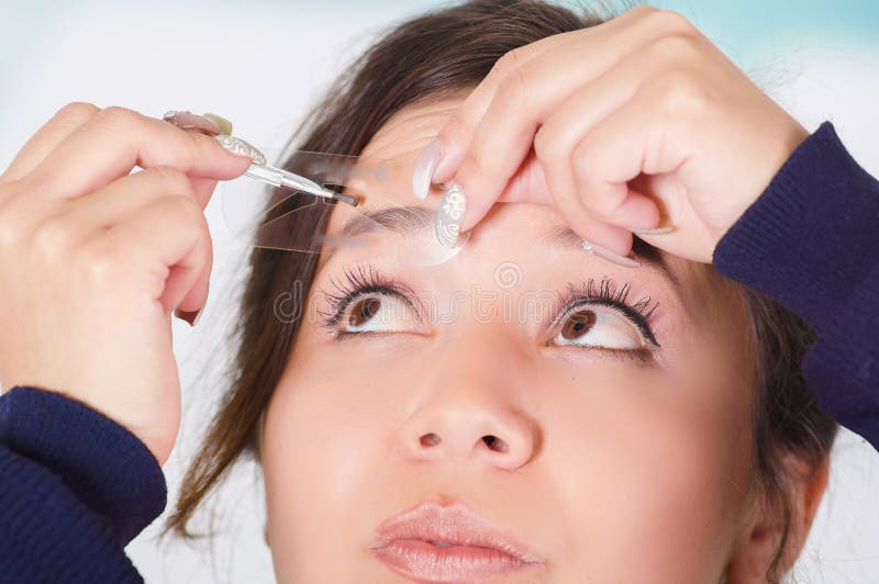 Portrait de la jeune belle femme faisant un désordre dans son sourcil à un arrière-plan brouillé photo stock Portrait de la jeune belle femme faisant un désordre dans son sourcil à un arrière-plan brouillé photo stock