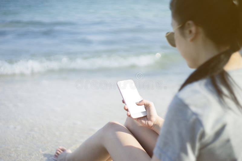 Portrait de la jeune femme asiatique à l'aide du téléphone intelligent à la plage Concept de technologie fond brouillé de mer de images stock Portrait de la jeune femme asiatique à l'aide du téléphone intelligent à la plage Concept de technologie fond brouillé de mer de images stock