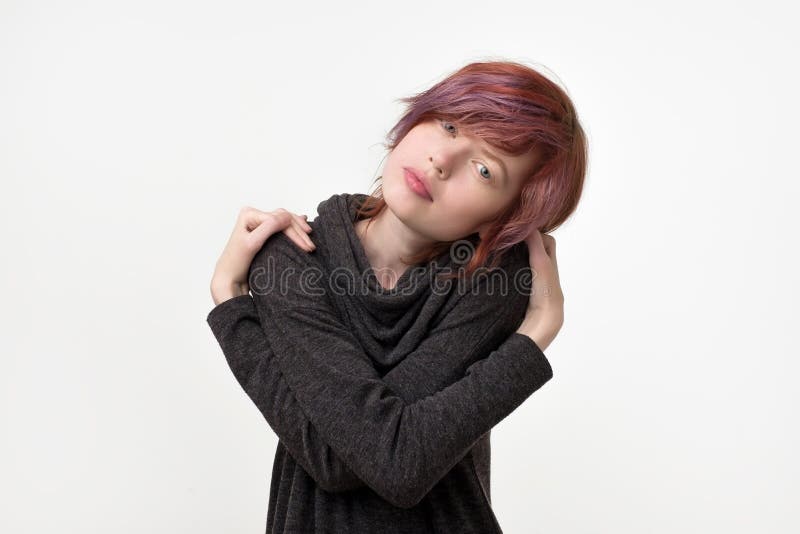 Portrait de la jolie femme informelle peu commune avec la coiffure colorée feignant comme elle s'étreint Étant fier photographie stock Portrait de la jolie femme informelle peu commune avec la coiffure colorée feignant comme elle s'étreint Étant fier photographie stock