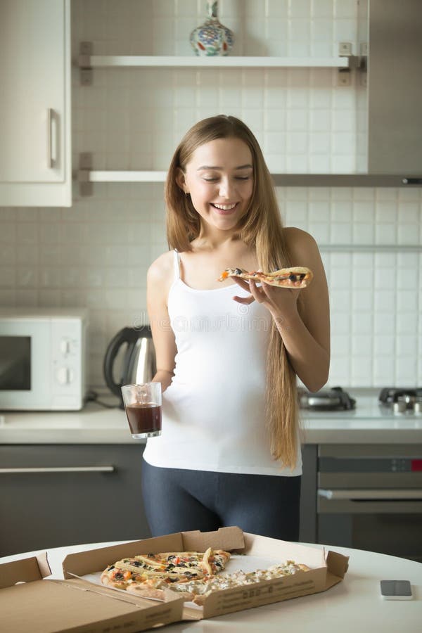 Portrait de la position de sourire de fille, participation une tranche de pizza photos stock Portrait de la position de sourire de fille, participation une tranche de pizza photos stock