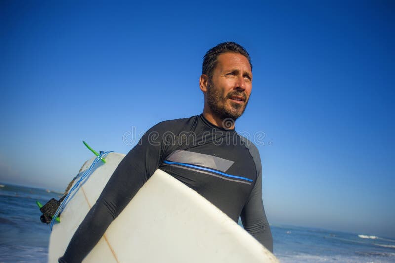 Portrait de mode de vie de l'homme attirant et frais 3os de surfer ? 40s dans le maillot de bain surfant du n?opr?ne posant avec photos stock Portrait de mode de vie de l'homme attirant et frais 3os de surfer ? 40s dans le maillot de bain surfant du n?opr?ne posant avec photos stock