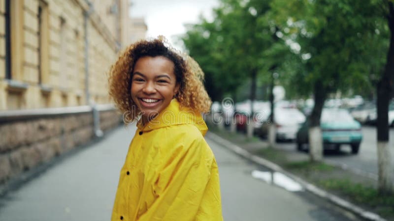 Portrait de mouvement lent du joli étudiant d'Afro-américain de jeune femme marchant dans la rue, tournant et regardant l'apparei clips vidéos