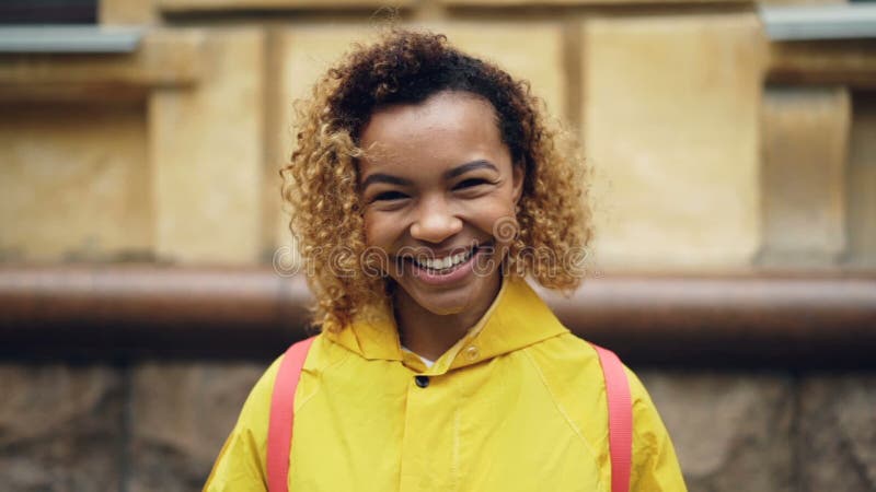 Portrait de mouvement lent de femme heureuse d'Afro-américain avec les cheveux bouclés regardant l'appareil-photo et souriant alo banque de vidéos