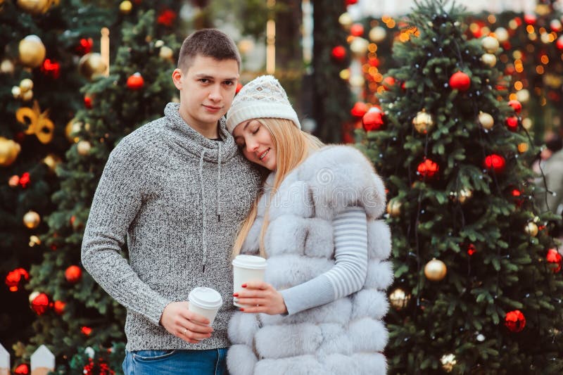 portrait de Noël des ajouter heureux au vin chaud ou au thé chaud marchant sur des rues de ville décorées pendant des vacances image libre de droits portrait de Noël des ajouter heureux au vin chaud ou au thé chaud marchant sur des rues de ville décorées pendant des vacances image libre de droits