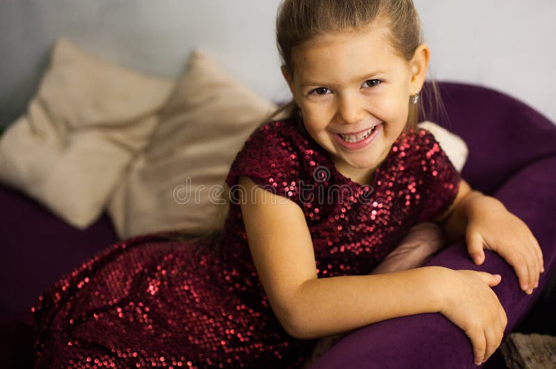 Portrait de petite fille dans la robe de bordo sur le sofa images libres de droits Portrait de petite fille dans la robe de bordo sur le sofa images libres de droits