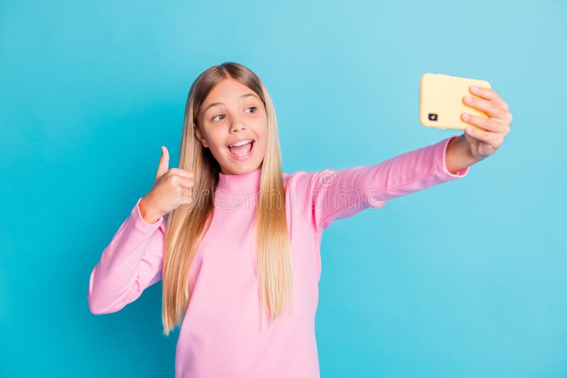 Portrait de photo du joli préadolescent féminin en tenant le selfie montrant le geste de thumbup isolés sur la couleur lumineuse d photographie stock
