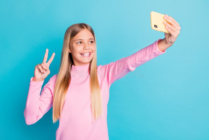 Portrait de photo du joli préadolescent féminin en tenant le selfie montrant le geste de vsign avec deux doigts isolé sur la sarce photo libre de droits