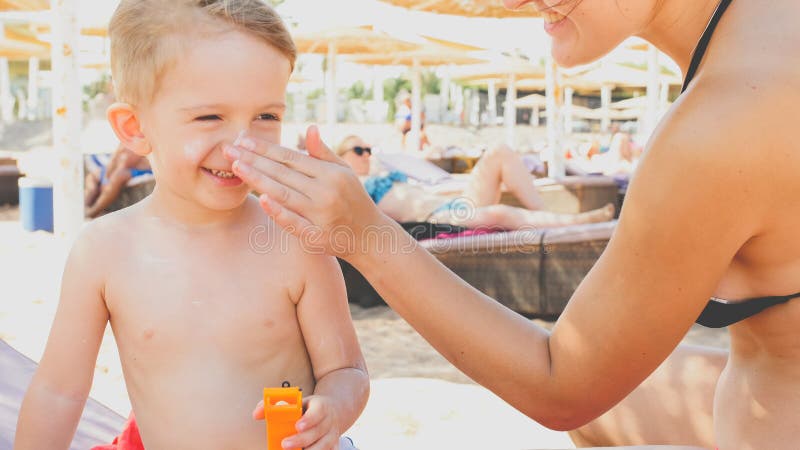 Portrait de plan rapproch? du sourire 3 ann?es de gar?on d'enfant en bas ?ge d?tendant sur la plage de mer avec la jeune m?re App image libre de droits Portrait de plan rapproch? du sourire 3 ann?es de gar?on d'enfant en bas ?ge d?tendant sur la plage de mer avec la jeune m?re App image libre de droits