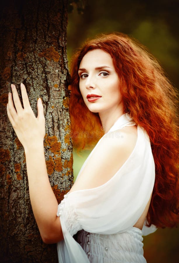 Portrait de plan rapproché d'une belle femme de gingembre près de l'arbre images libres de droits Portrait de plan rapproché d'une belle femme de gingembre près de l'arbre images libres de droits