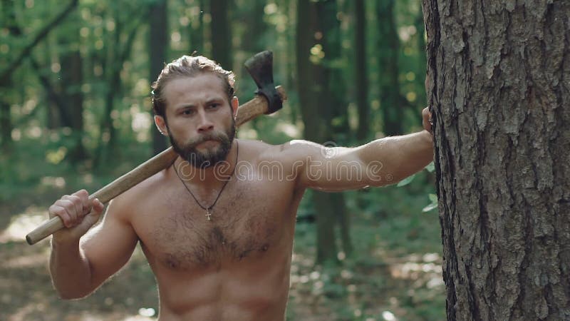 Portrait de promenade barbue belle d'homme avec la hache dans la forêt lentement