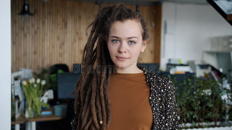 Portrait de ralenti de jeune femme créative avec des dreadlocks debout au bureau avec la face sérieux banque de vidéos