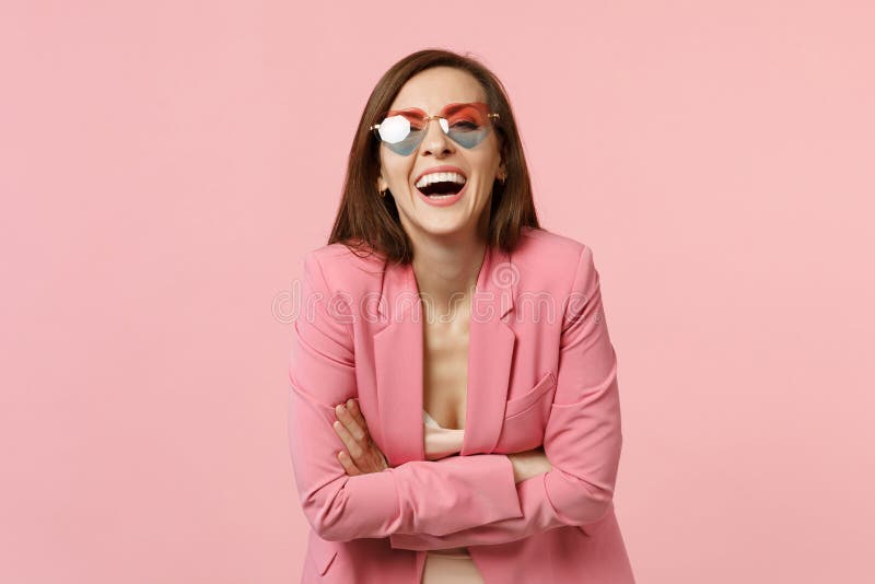 Portrait de rire la jeune femme heureuse gaie en verres de coeur se tenant, jugeant des mains pliées d'isolement sur le rose en p photos stock Portrait de rire la jeune femme heureuse gaie en verres de coeur se tenant, jugeant des mains pliées d'isolement sur le rose en p photos stock