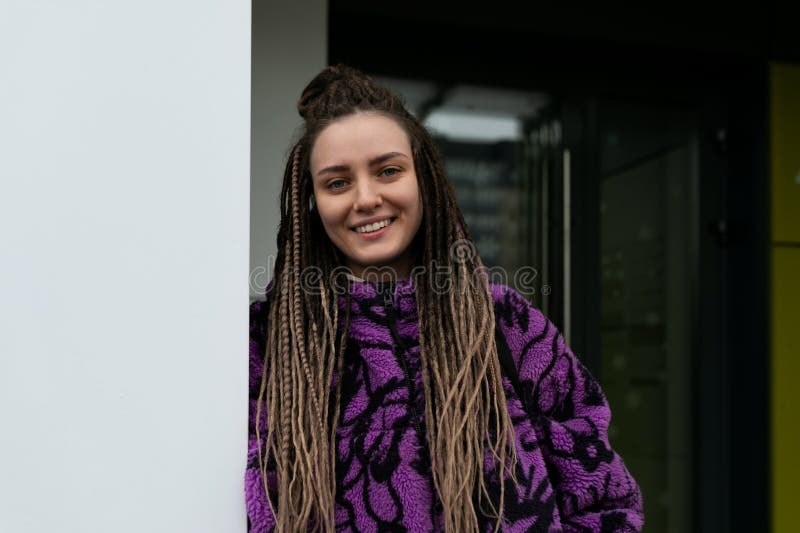 Portrait de rue d'une jeune femme percée et cadenas africains debout contre un mur photo stock