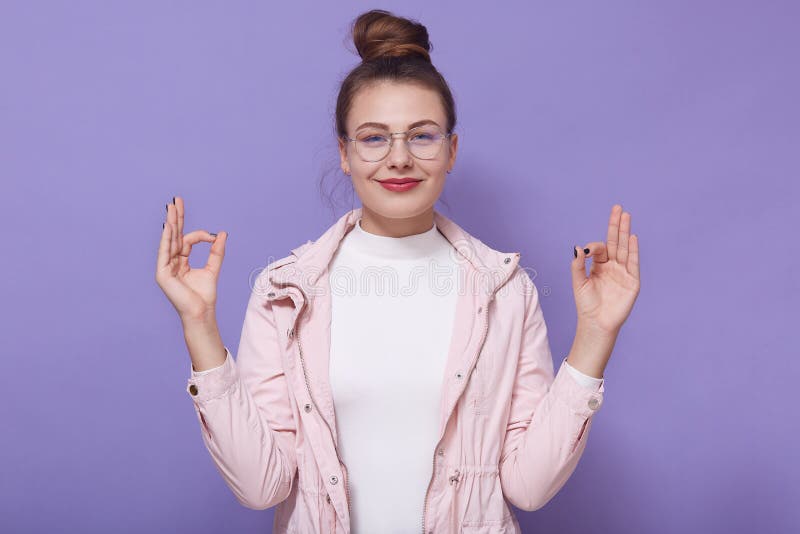 Portrait de studio de la jeune femme agréable positive avec le rouleau augmentant les mains à l'expression du visage souriant sinc photo stock