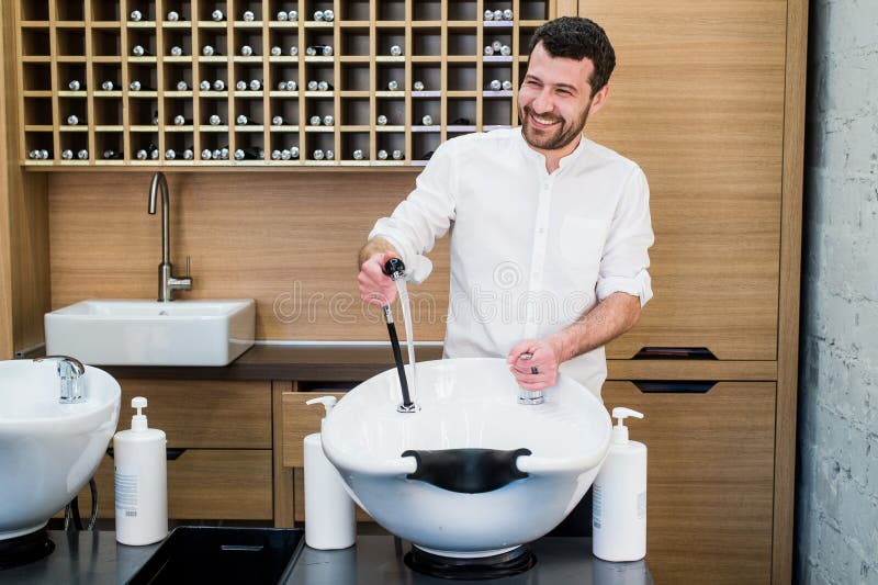 Portrait De Coiffeur Heureux Avec Robinet D'eau Près De L'évier Au Salon De  Coiffure