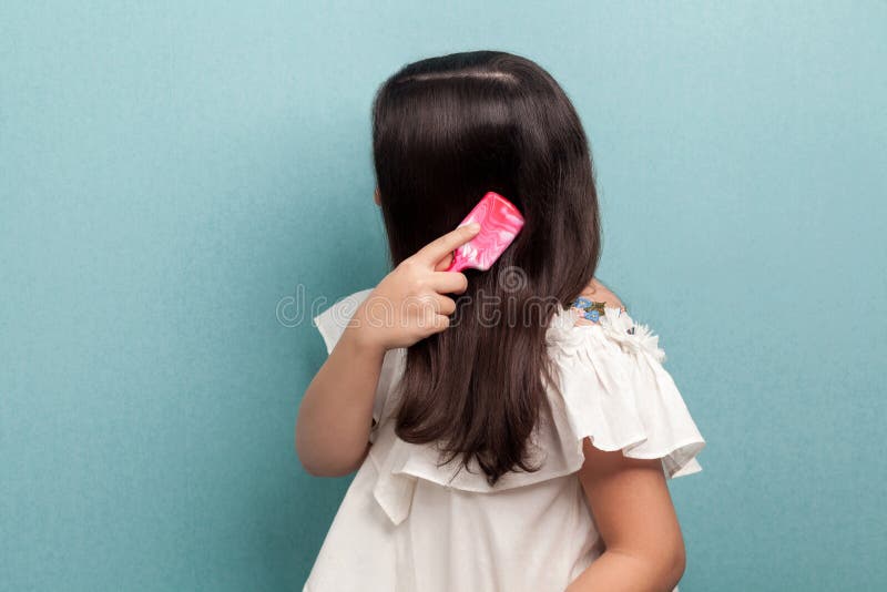 Portrait de vue de c? t? de fille d'adolescent dans la position blanche de robe, faisant l'attention et peignant des cheveux de br photo libre de droits
