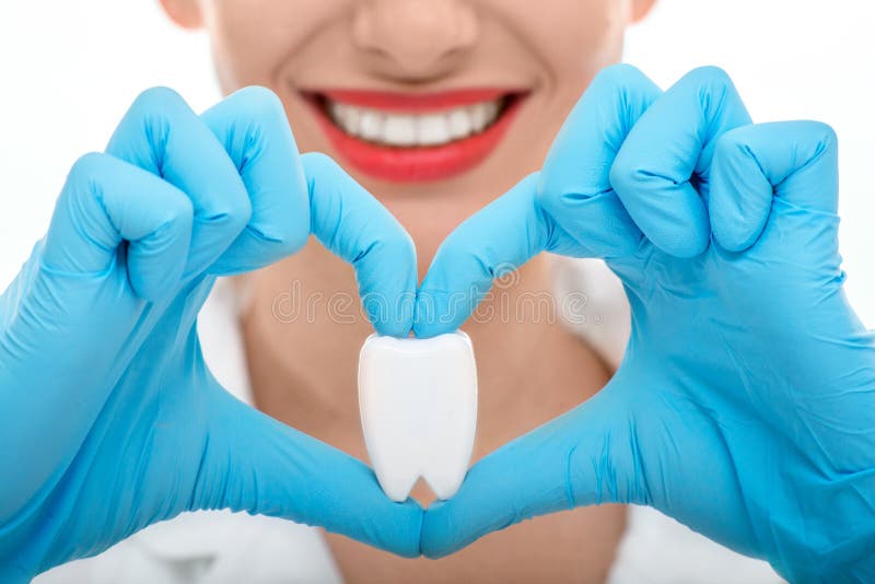 Schließen Porträt der Jungen Frau Zahnarzt mit gesunden breiten lächeln holding künstliche zahn auf weißem hintergrund.