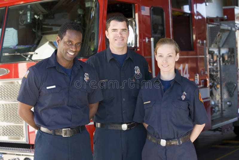 Portrait of firefighters standing by a fire engine smiling. Portrait of firefighters standing by a fire engine smiling