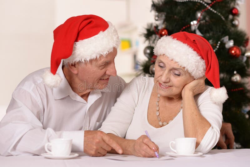 Portrait des chapeaux de port de vacances de Noël de vieux couples d'une manière amusante avec des tasses de thé images stock Portrait des chapeaux de port de vacances de Noël de vieux couples d'une manière amusante avec des tasses de thé images stock