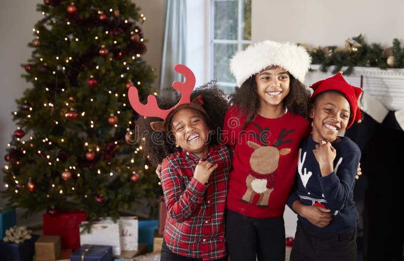 Portrait des enfants portant les pullovers de fête et des chapeaux célébrant Noël à la maison ensemble photo libre de droits Portrait des enfants portant les pullovers de fête et des chapeaux célébrant Noël à la maison ensemble photo libre de droits