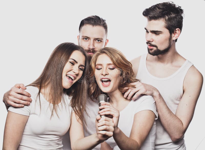 Portrait des filles heureuses et des types chantant dans le microphone au-dessus du fond blanc photo libre de droits Portrait des filles heureuses et des types chantant dans le microphone au-dessus du fond blanc photo libre de droits