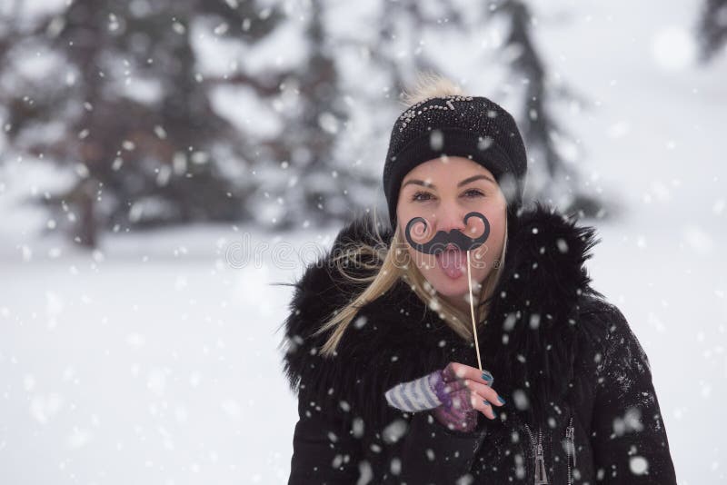 Portrait des jeunes femmes avec les appui verticaux de papier de moustache le jour neigeux images stock Portrait des jeunes femmes avec les appui verticaux de papier de moustache le jour neigeux images stock