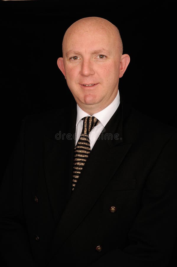 Portrait of smiling middle aged bald businessman in smart suit on black background. Portrait of smiling middle aged bald businessman in smart suit on black background.