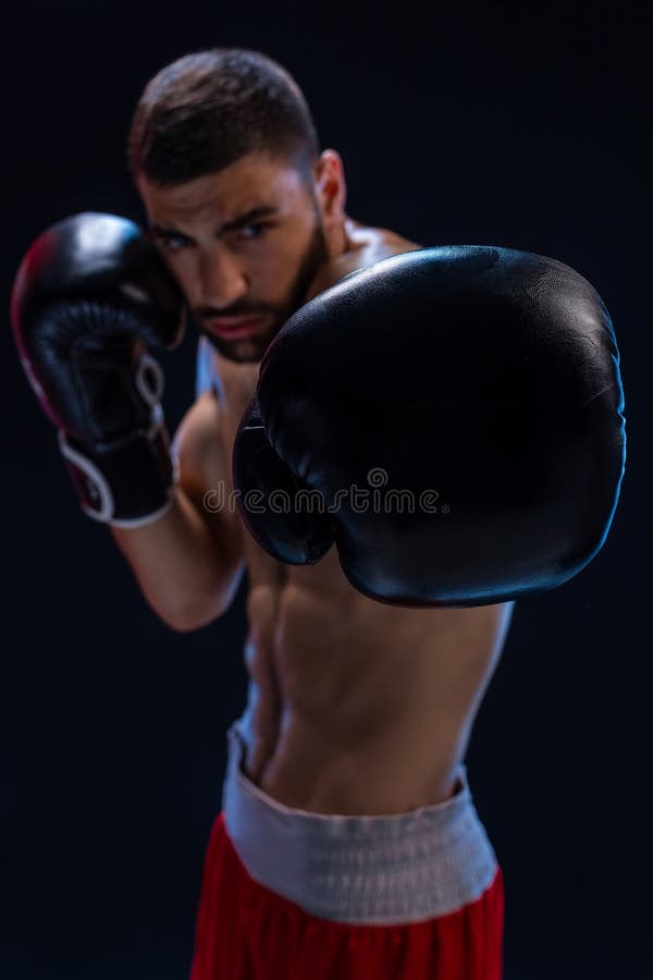 Portrait du boxeur masculin dur posant dans la position de boxe sur le fond noir photographie stock libre de droits Portrait du boxeur masculin dur posant dans la position de boxe sur le fond noir photographie stock libre de droits