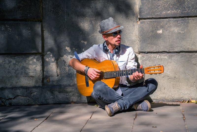 Portrait du jeune homme musicien de rue qui joue de la guitare sur un pavé de ville La liberté, la musique et l'art concept Image
