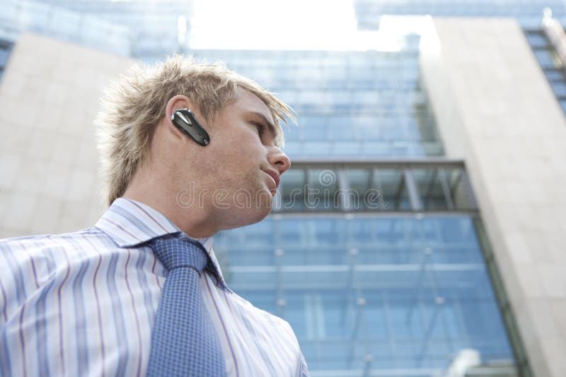 Joven emprendedor manos gratis dispositivos sobre el hablar sobre el teléfono, en financiero distrito.