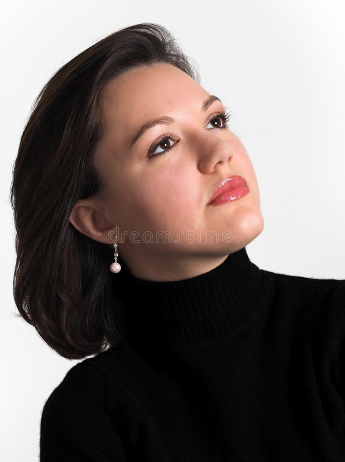 Head and shoulders portrait of an attractive young woman looking up; dark hair, dark eyes, dressed in dark blouse; vertical format; white background; studio;. Head and shoulders portrait of an attractive young woman looking up; dark hair, dark eyes, dressed in dark blouse; vertical format; white background; studio;