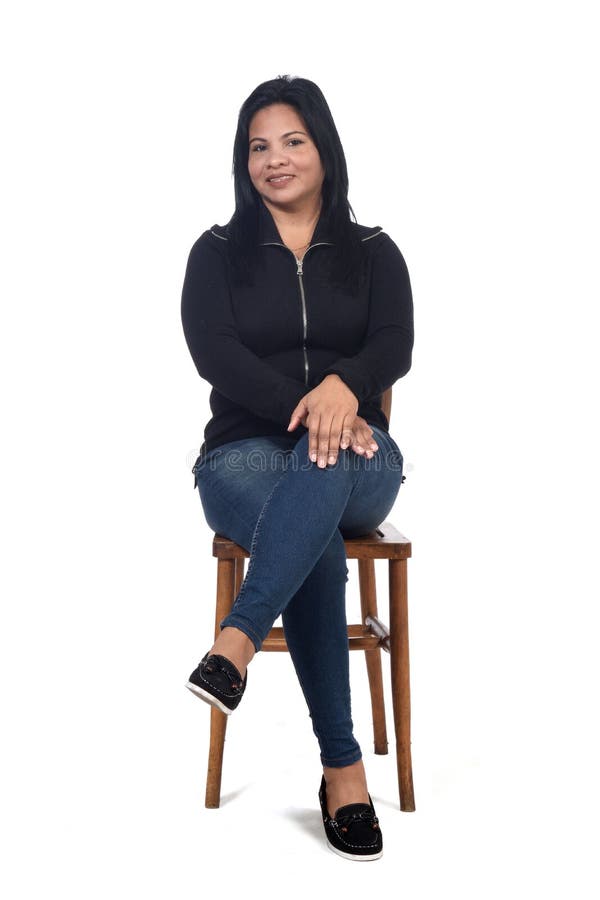 Portrait einer Frau, die auf einem Stuhl in den weißen Hintergrundbeinen sitzt, die Daumen stockfoto