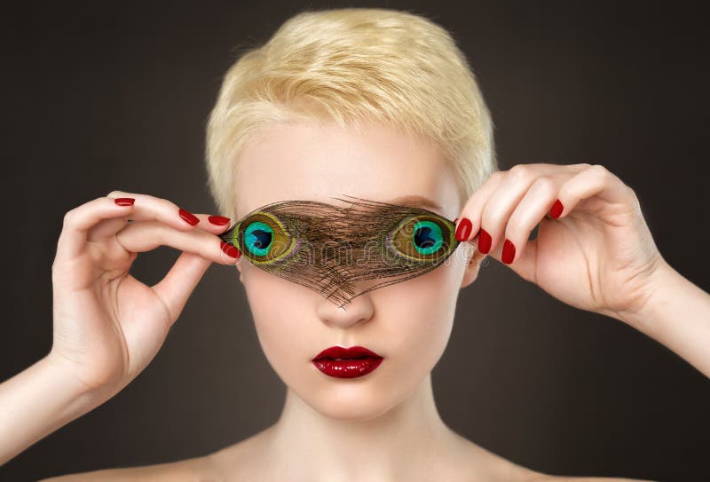 Portrait of a beautiful woman with short blonde hair, beautiful fresh make-up and red lips, with feather earrings on black background. Makeup concept. Portrait of a beautiful woman with short blonde hair, beautiful fresh make-up and red lips, with feather earrings on black background. Makeup concept.