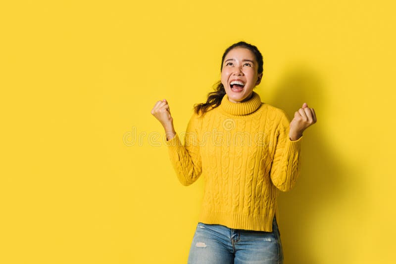 Portrait einer glücklichen Asiatin, die einen aufgeregten und feiernden Erfolg isoliert von gelbem Hintergrund schreit. Folgen Si stockbild