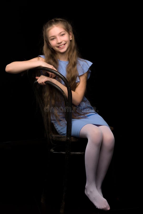 Portrait eines kleinen Mädchens, das auf einem alten Wiener Stuhlschwarzhintergrund sitzt. lizenzfreies stockfoto