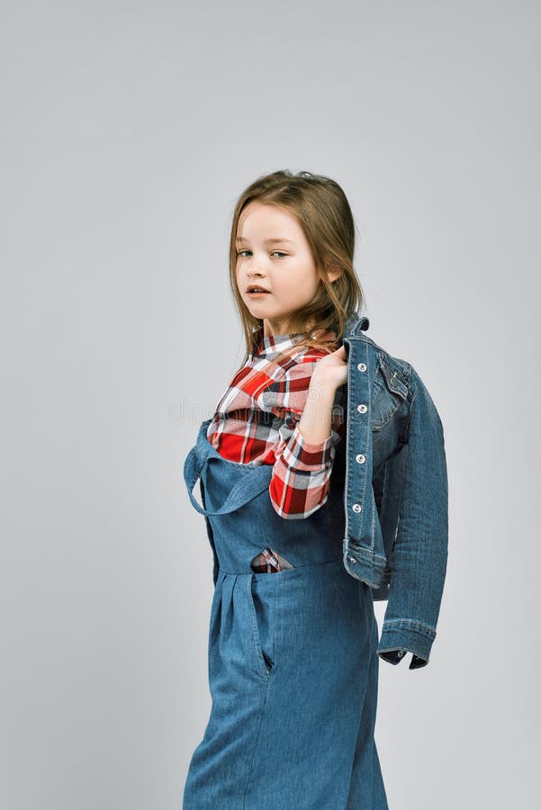 Portrait eines modernen Mädchens im Overalls eines karierten Hemds und des Denims. Studiomodeschießen lizenzfreie stockfotografie