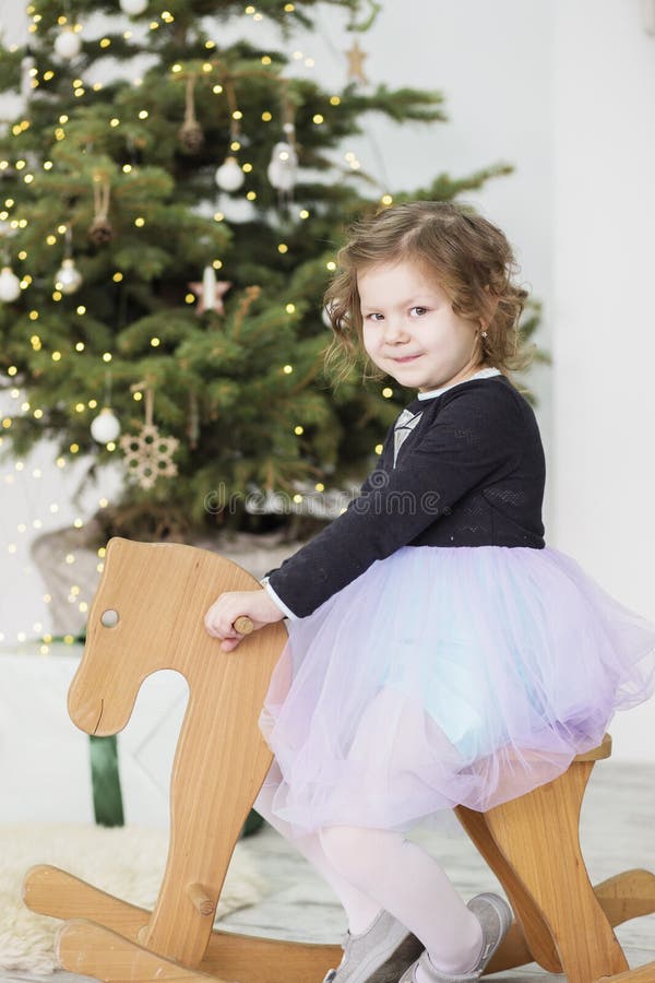 Portrait eines netten kleinen M? dchens kleines M? dchen unter Weihnachtsdekorationen M? dchen, das ein Schwingrotwild reitet lizenzfreies stockbild