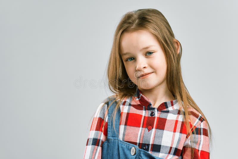 Portrait eines netten kleinen Mädchens im Overalls eines karierten Hemds und des Denims. Studiomodeschießen stockbild