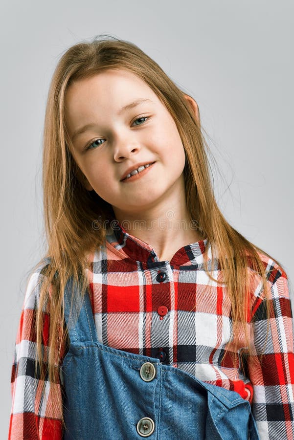 Portrait eines netten kleinen Mädchens im Overalls eines karierten Hemds und des Denims. Studiomodeschießen lizenzfreie stockfotos