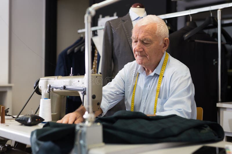 Portrait of Elderly Tailor Working on Sewing Machine at Studio Stock